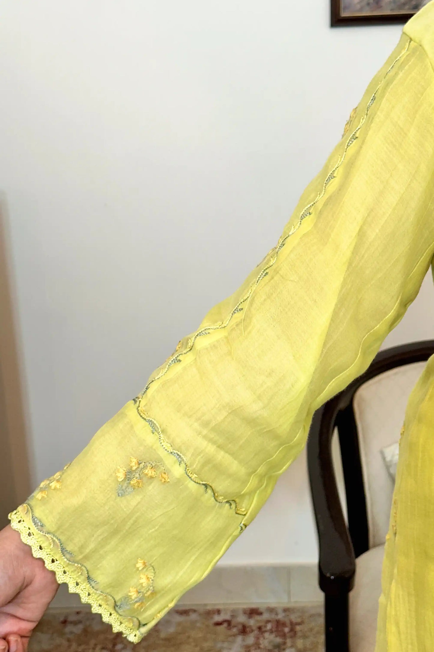 Close-up of a sleeve on a lemon-yellow chanderi kurta, showing floral resham embroidery and a scalloped lace trim at the cuff.