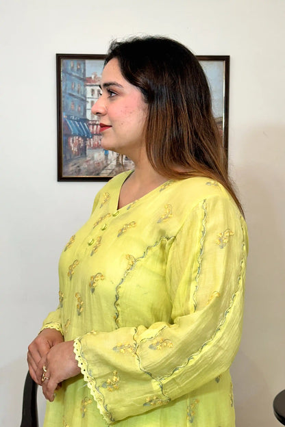 Side view close-up of a lemon-yellow chanderi kurta, showing floral resham embroidery around the button placket and sleeve.