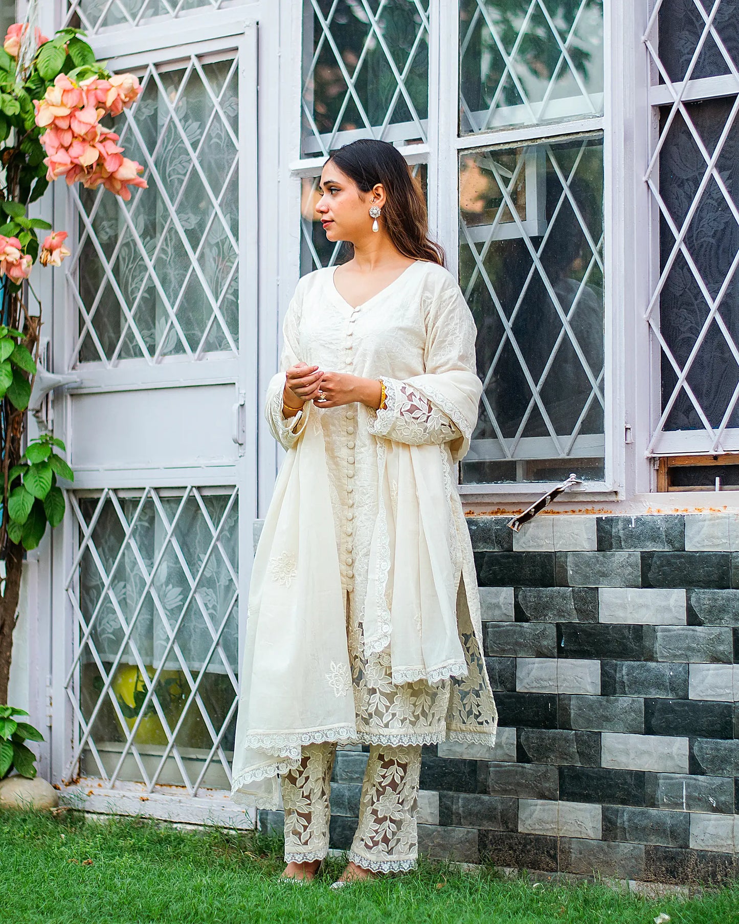 Indian model in a white cotton kurta, paired with a coordinating dupatta and trousers, featuring intricate floral cutwork details.