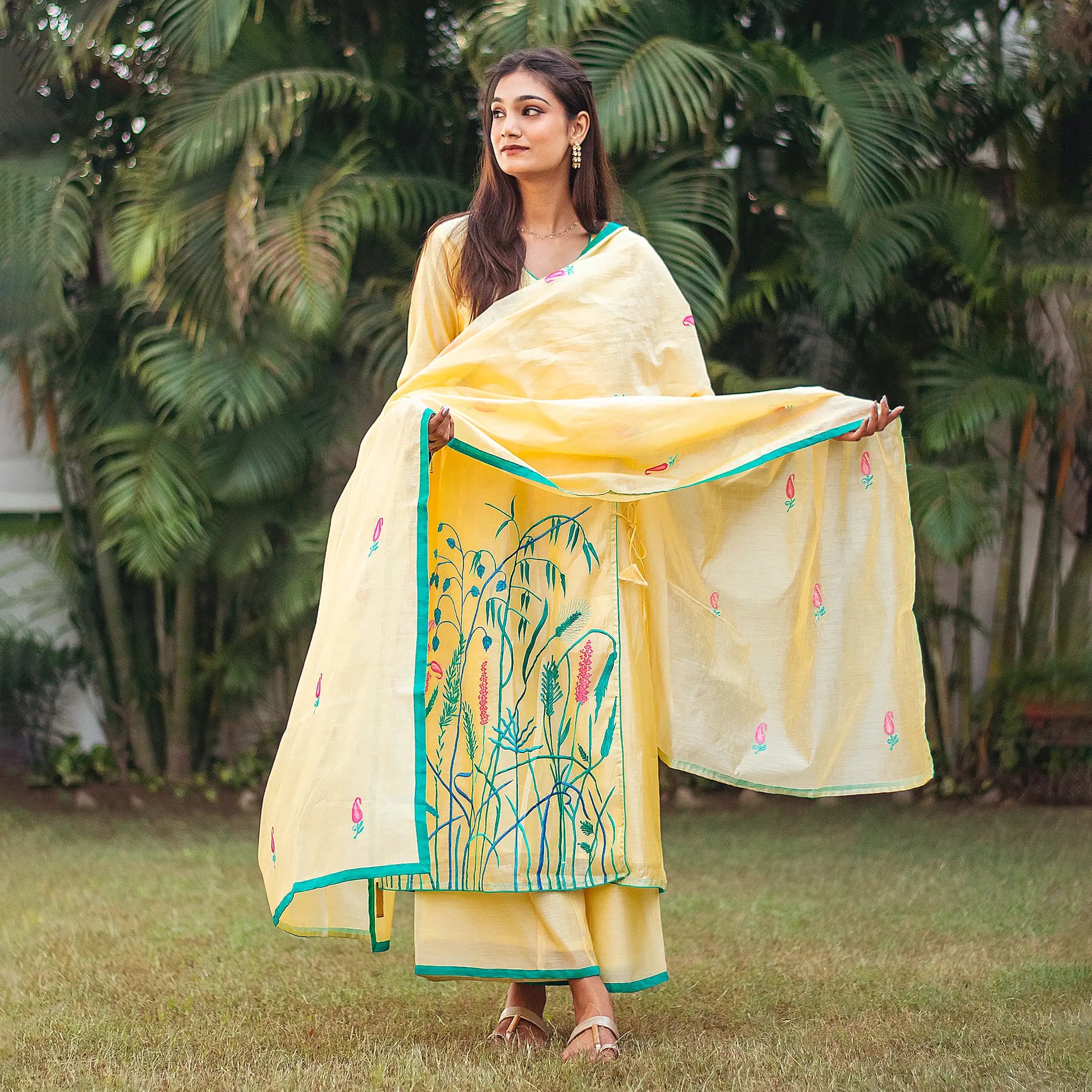 Indian woman wearing a yellow chanderi angrakha and dupatta adorned with floral embroidery, styled with a matching palazzo.