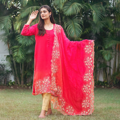 Indian model dressed in a red organza kurta and dupatta featuring gold floral cutwork, complemented by golden brocade trousers.