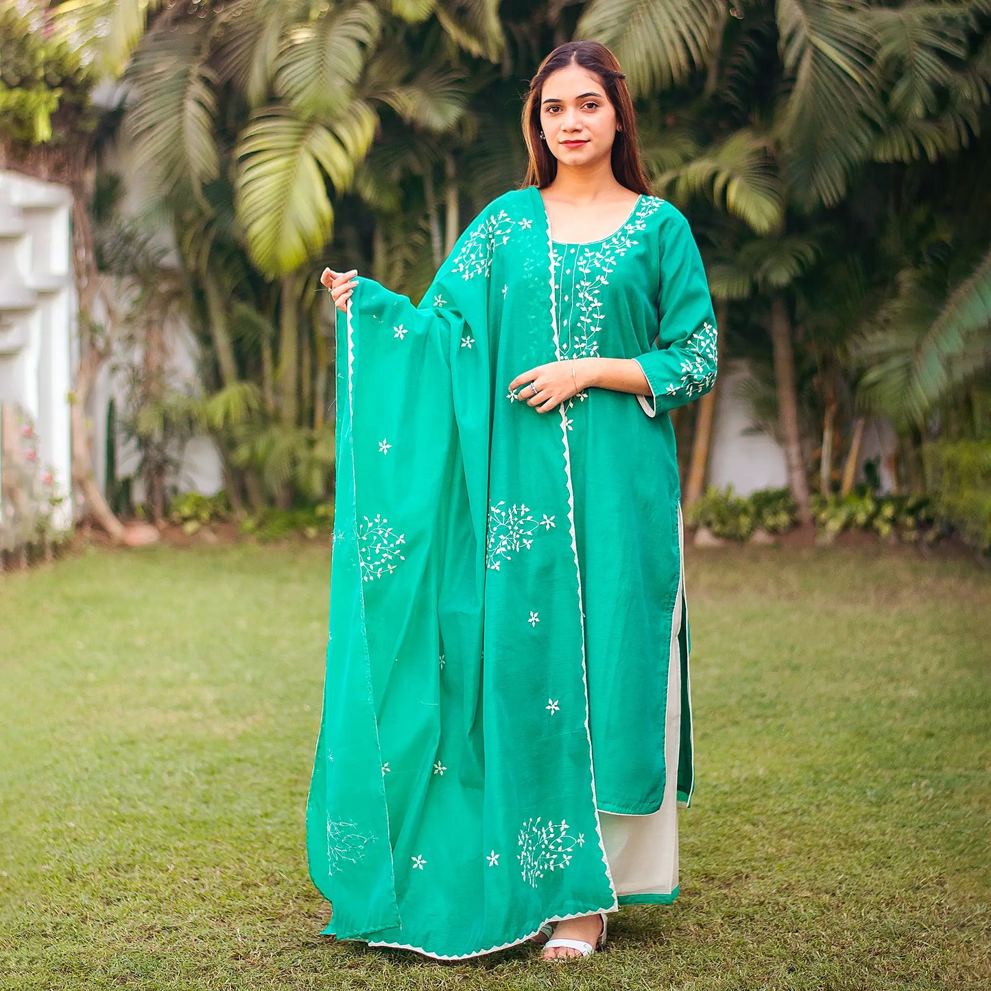 Indian model posing in a green chanderi kurti and dupatta with applique work paired with white palazzo, complete attire is visible.