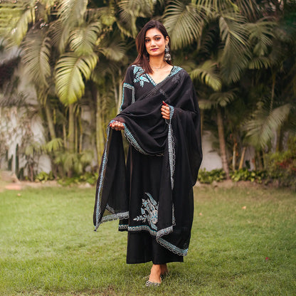 Indian model posing in a black chanderi angrakha and dupatta with white and blue resham embroidery, paired with matching  palazzo.