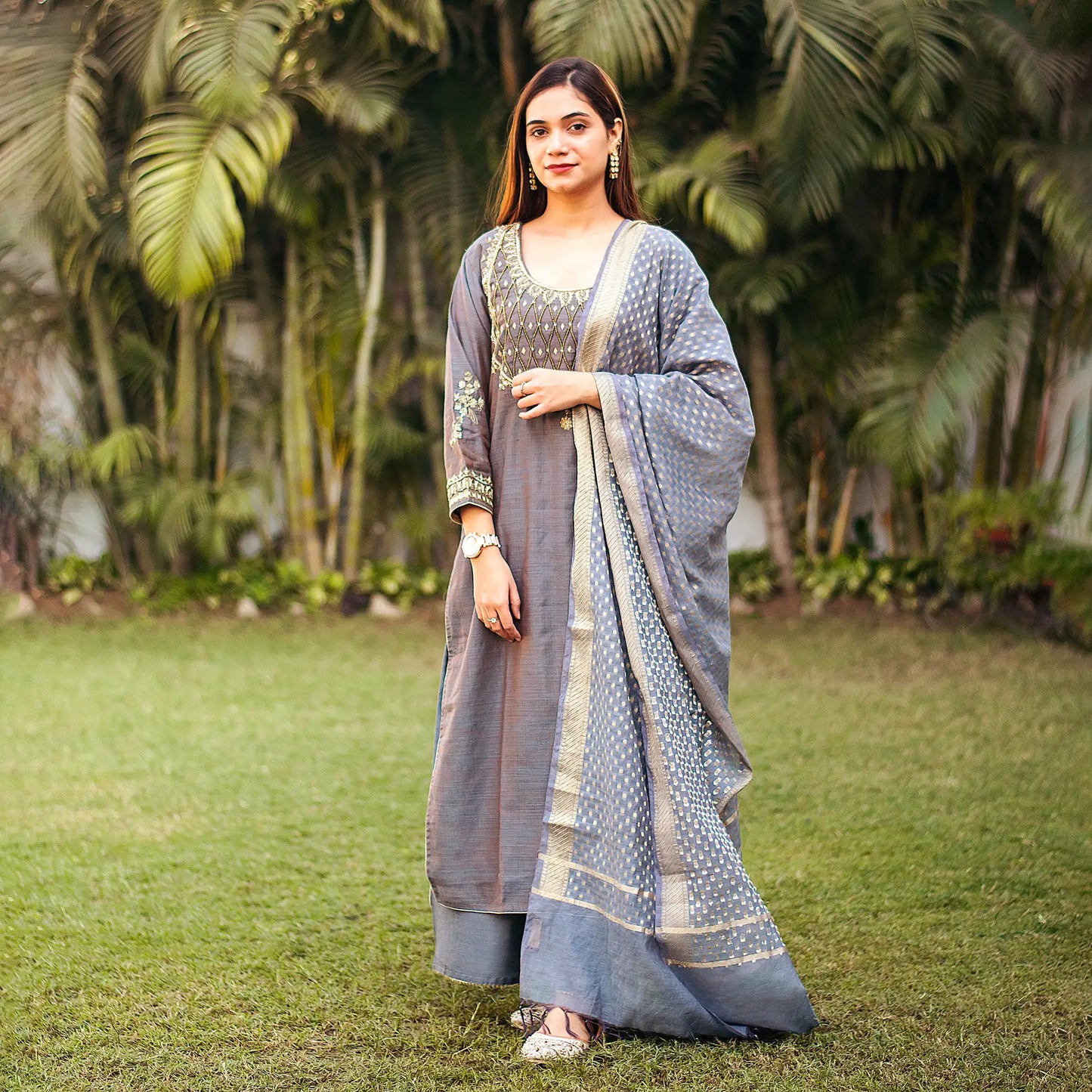 ndian model dressed in a grey silk kurta adorned with zardozi work, complemented by a matching dupatta and palazzo.