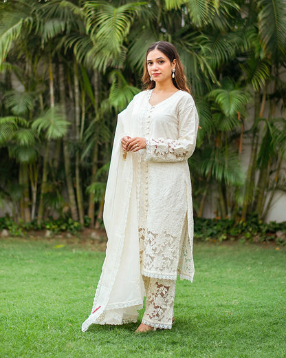 Indian model dressed in a white cotton kurta set with matching dupatta and trousers, all adorned with floral cutwork.