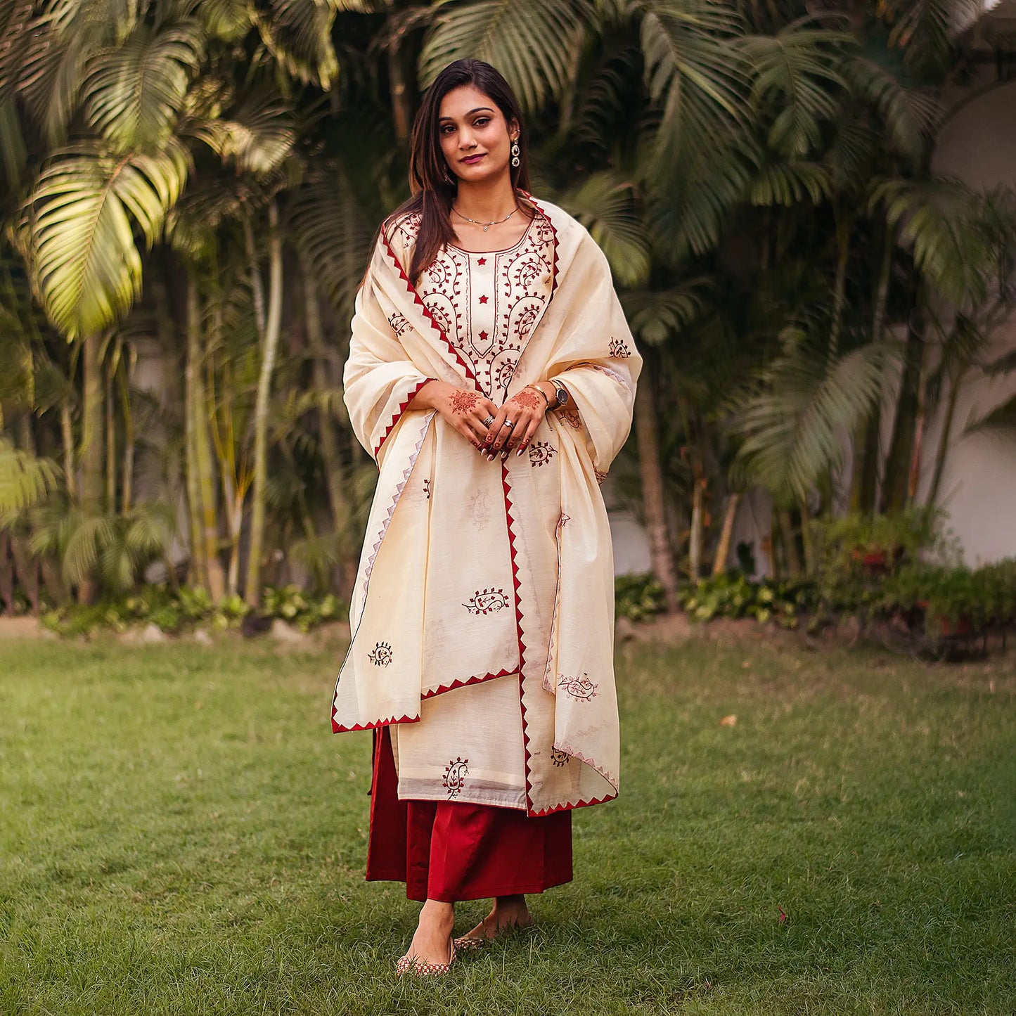 Indian woman dressed in a beige chanderi kurta and dupatta with maroon applique work and a contrasting maroon palazzo.