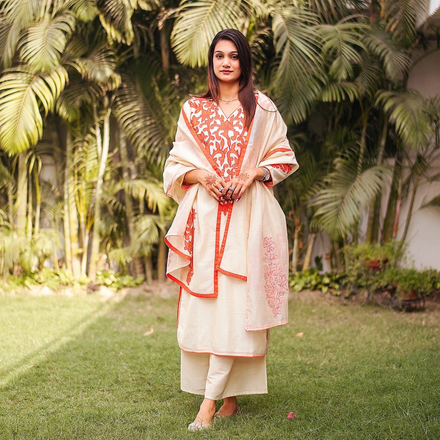 Indian model in a beige kurta set with orange floral vines on the yoke, complemented by a beige dupatta and palazzo.