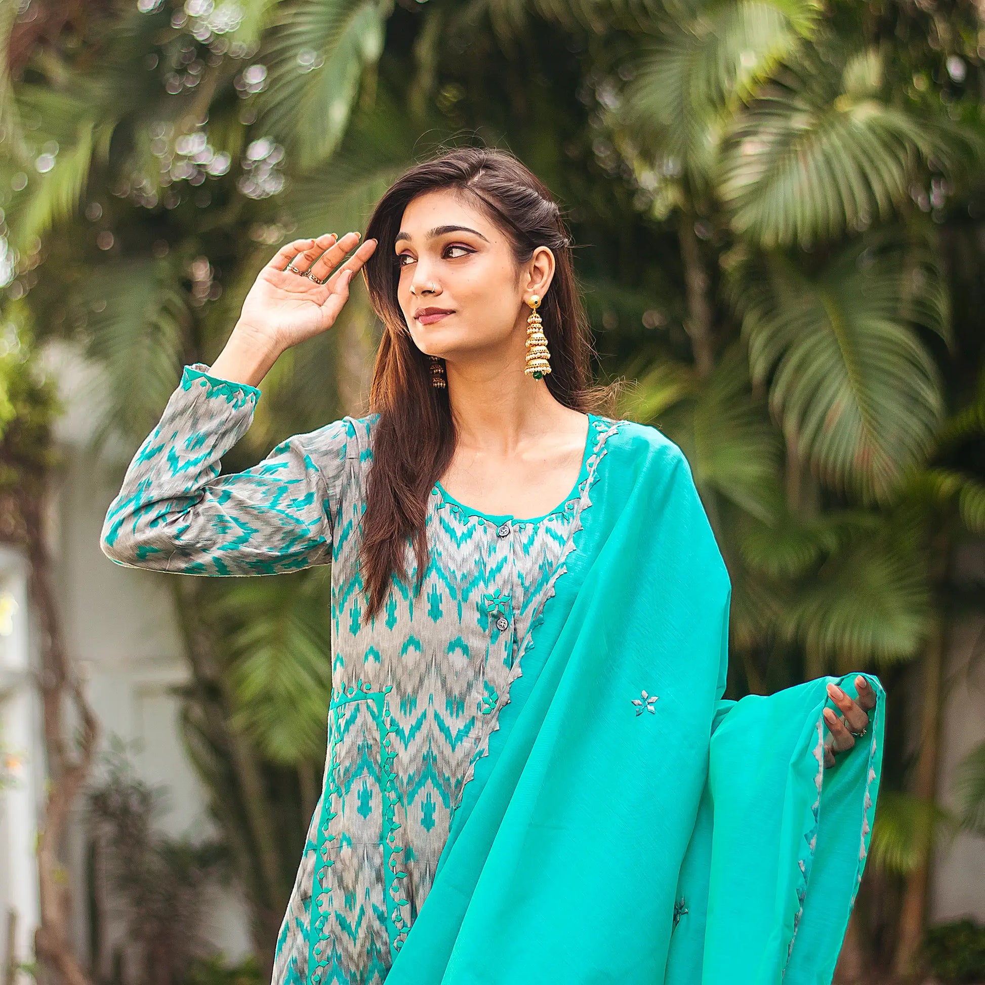  Indian lady poses in a grey and green kurta with ikat print, adorned with green applique motifs, paired with a green dupatta.