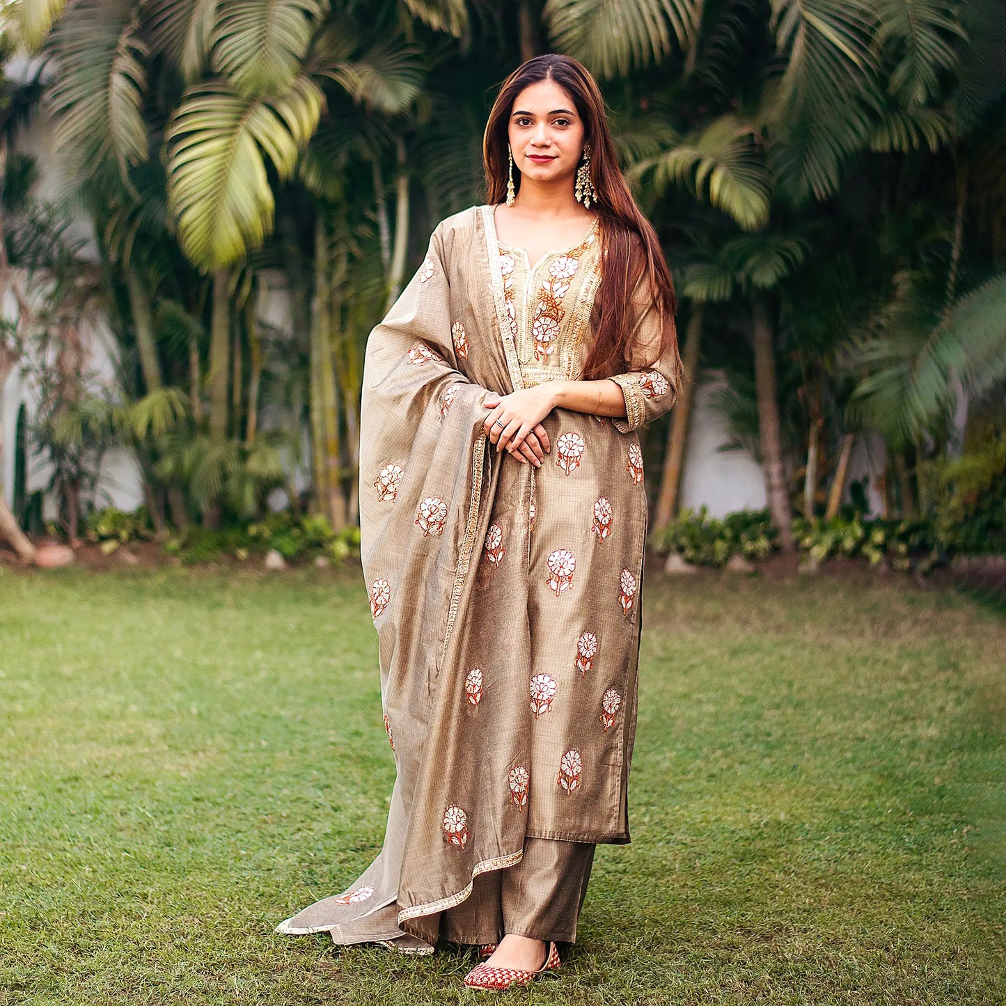 Indian model in a beige Chanderi kurta and dupatta adorned with golden gota patti work, styled with a matching beige palazzo.