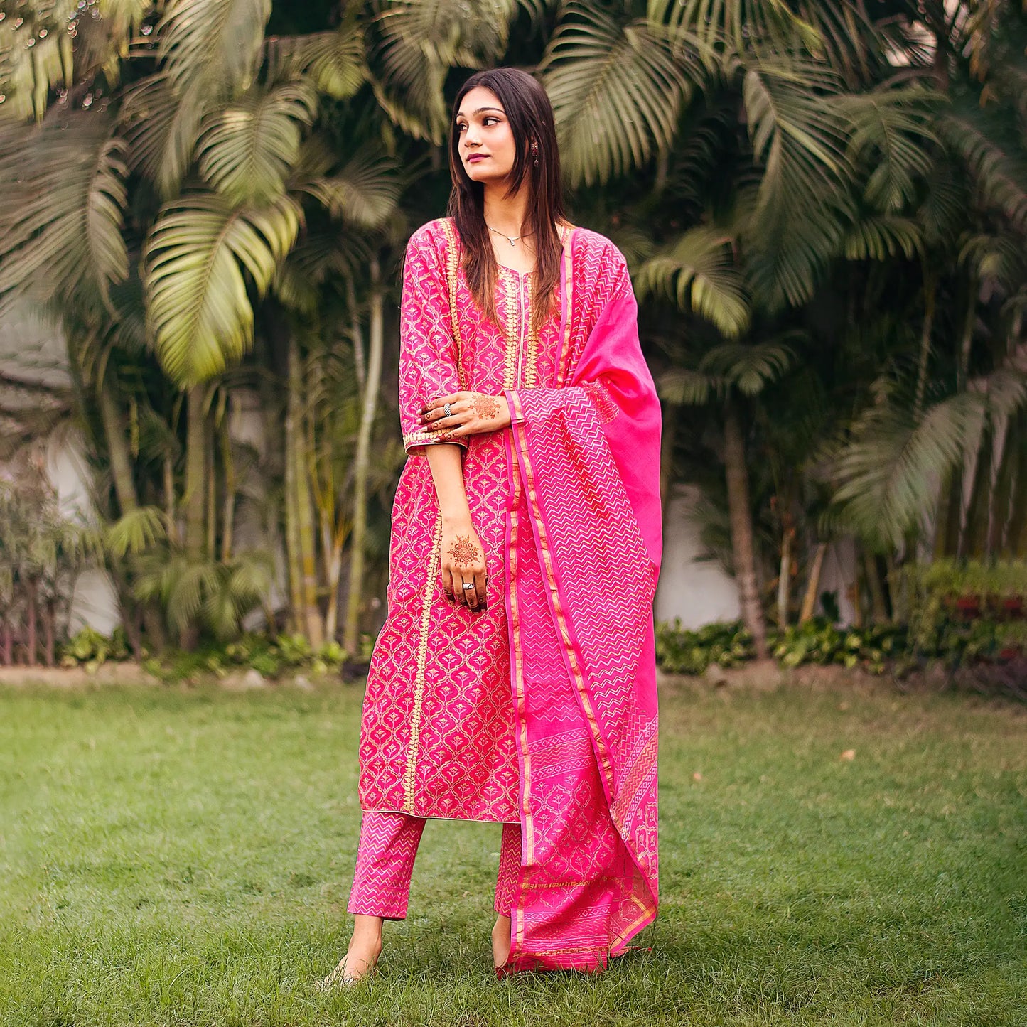 Indian model in a vibrant magenta kurta set featuring beige applique work, complemented by a foil-printed dupatta and trousers.