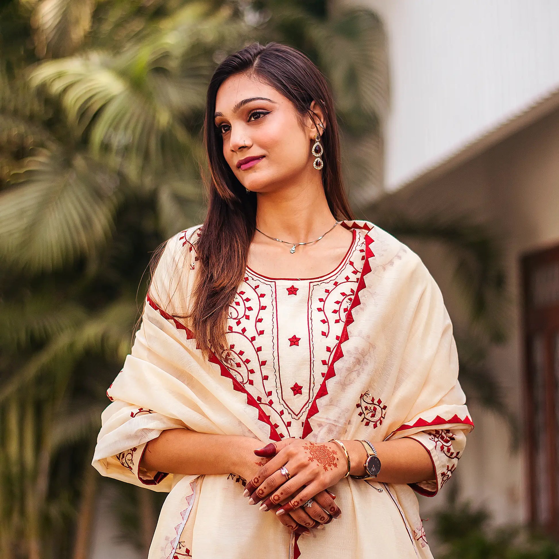 Close-up of an Indian model wearing a beige chanderi kurta with maroon applique motifs, holding a beige dupatta.