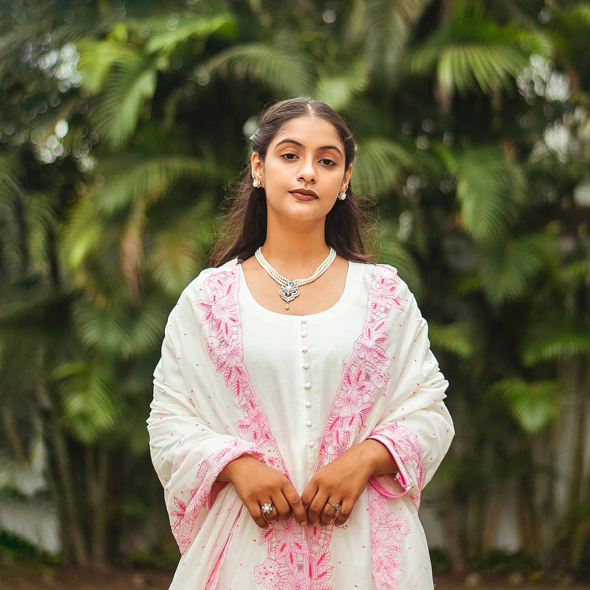 Close-up of the Indian model weaing  off-white chanderi kurta and dupatta with pink cutwork and sequins.