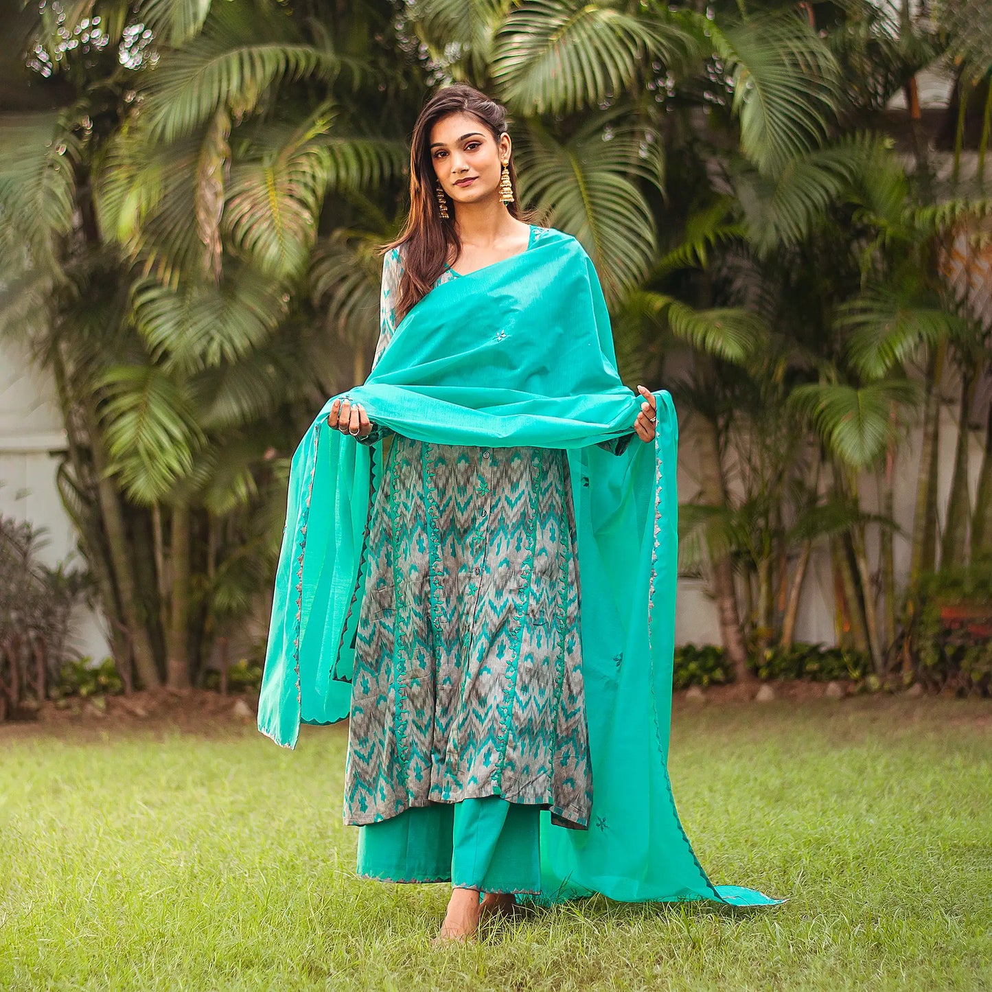 Indian woman poses in a grey and green A-line kurta with delicate green applique motifs, complemented by a green chanderi dupatta and palazzo.