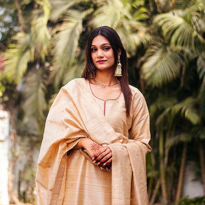 Close-up of an Indian model wearing a beige silk kurta with resham weave, holding a matching dupatta with banarasi motifs.