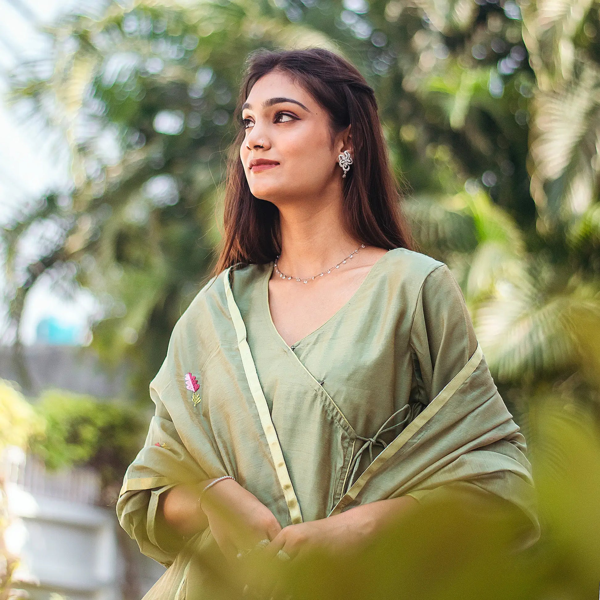 Upper front view of a model wearing the green kurta set, featuring a green chanderi angrakha with and a green chanderi embroidered dupatta.