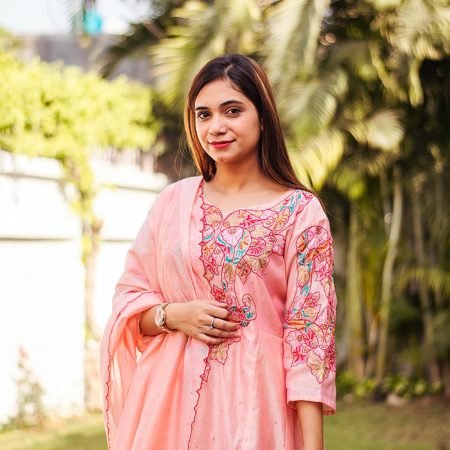 Indian model in a peach Chanderi kurta and dupatta with multicoloured resham embroidery and pink sequins.