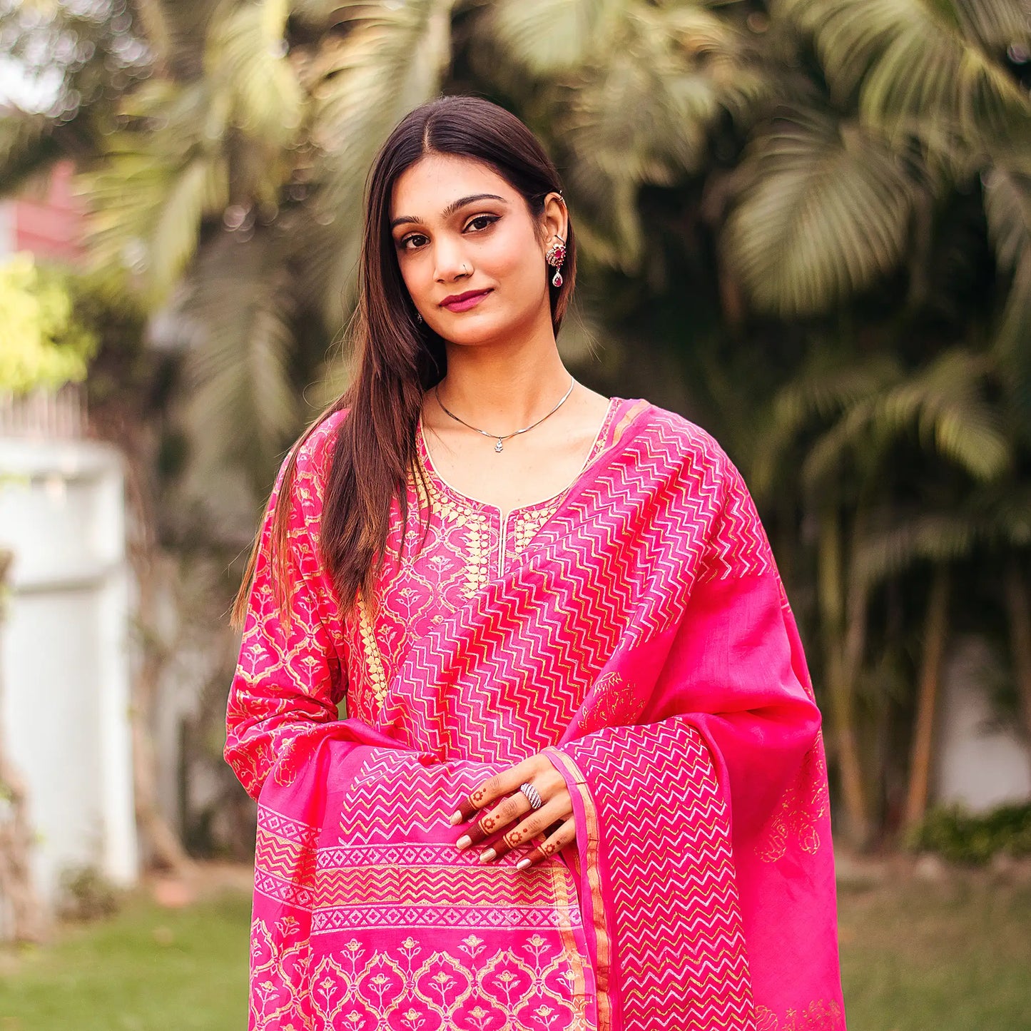 Close-up of an Indian model wearing a magenta chanderi kurta with beige applique motifs, holding a matching foil-printed dupatta.