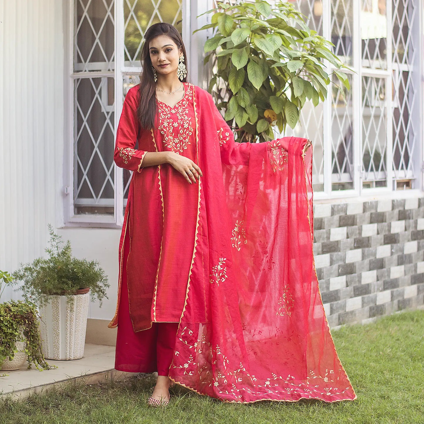 Indian lady poses in a red jute silk kurta and chanderi dupatta with beige applique work, complemented with a red palazzo.