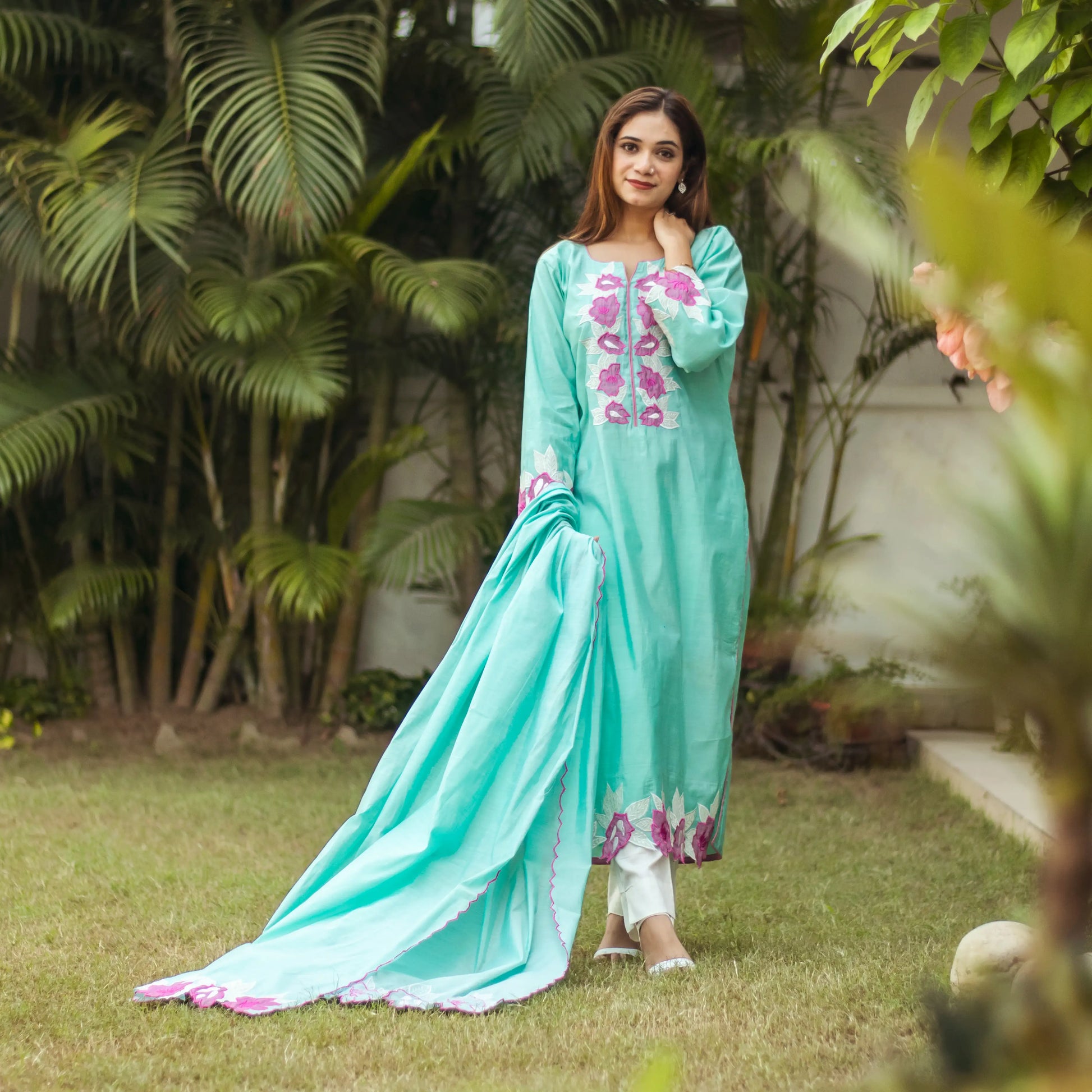 Indian woman dressed in a blue chanderi kurta with matching dupatta featuring purple floral patchwork, complemented by off-white trousers