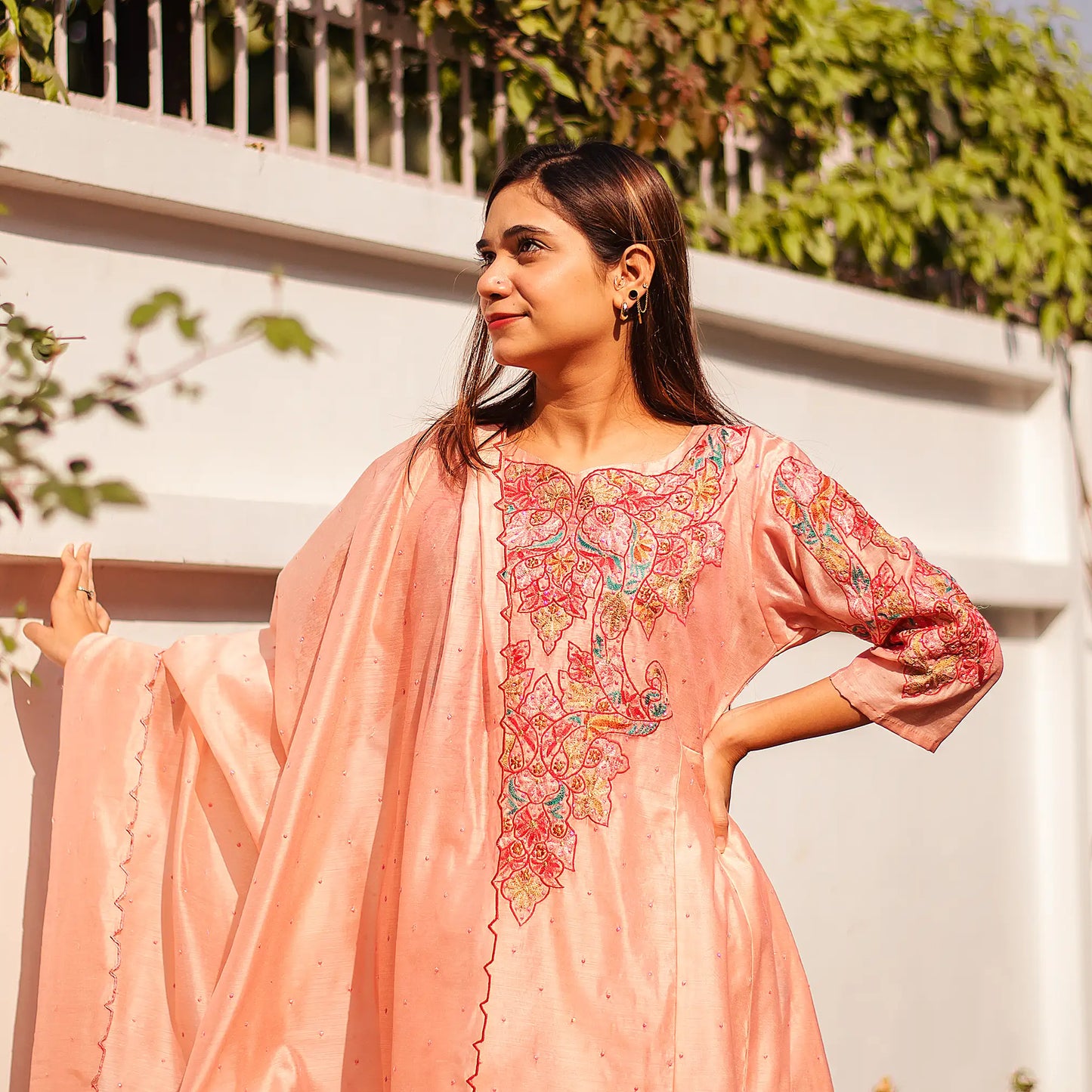 Indian lady wearing a peach Chanderi kurta adorned with colorful resham embroidery and a peach dupatta.