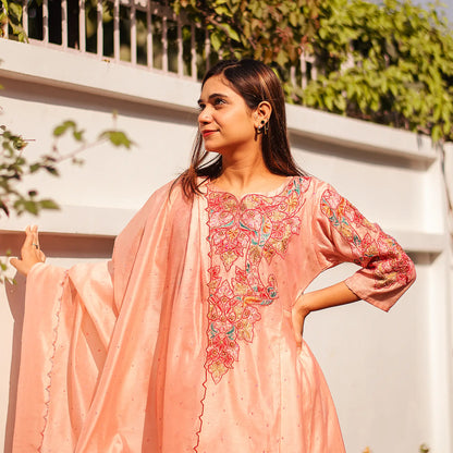 Indian lady wearing a peach Chanderi kurta adorned with colorful resham embroidery and a peach dupatta.