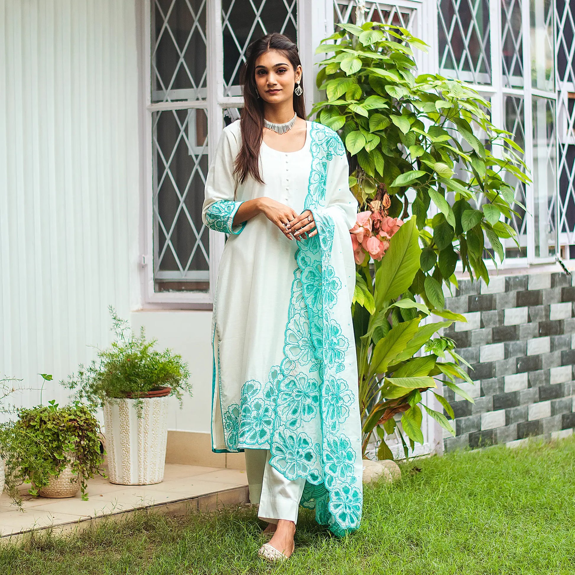 Model wearing the off-white Chanderi suit with cyan green floral cutwork, posing a little differently