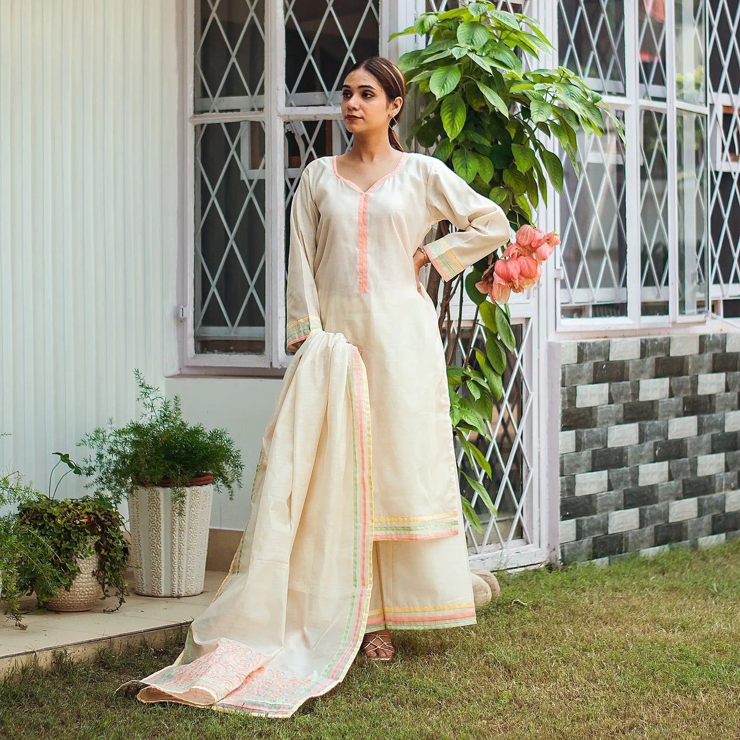 Indian model dressed in an off-white chanderi kurta with pastel piping, styled with a matching palazzo and dupatta featuring pastel patchwork.