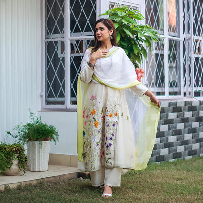 Indian model in an off-white angrakha kurta adorned with red, magenta, purple, and mustard flowers, paired with matching palazzo and chiffon dupatta.