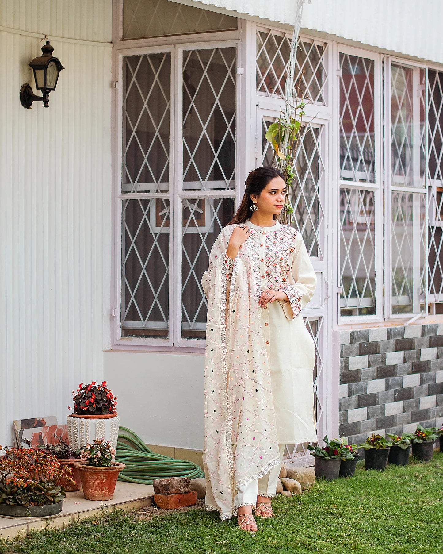 Indian girl in an off-white front-open cotton kurti with Kashmiri embroidery, complemented by a matching dupatta and trousers.