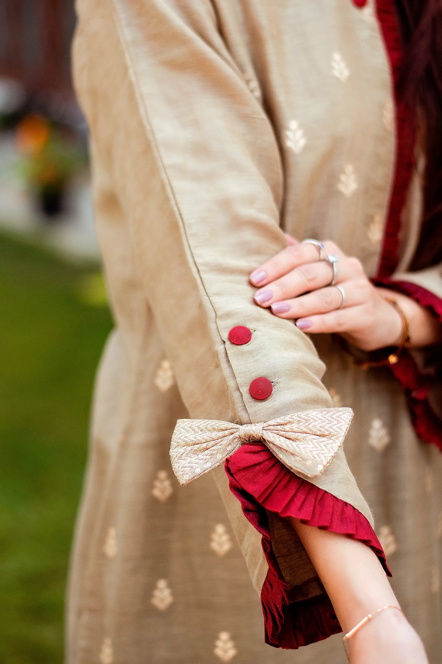 Close-up of hands of a woman wearing intricate taupe zari weave pattern on a linen kurta.