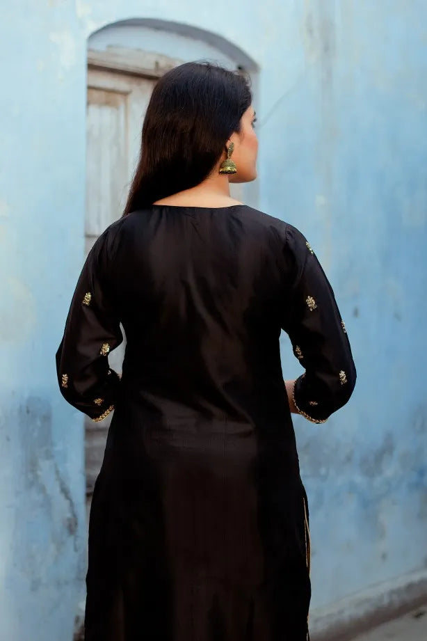 A stylish lady in a black silk kurta with intricate Zardozi work paired with black palazzo pants and a black Chanderi dupatta.