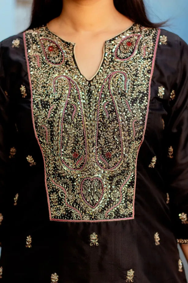 A fashionable woman dressed in a black silk kurta with Zardozi work and black silk palazzo pants, complemented with a black Chanderi dupatta.