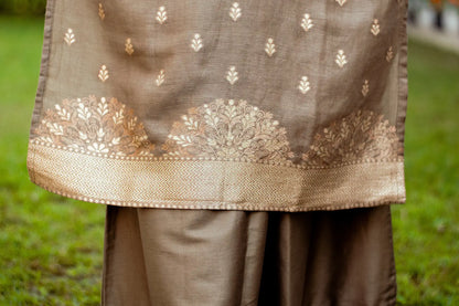 Close-up of the bottom hem of a linen kurta, featuring a delicate taupe zari weave pattern