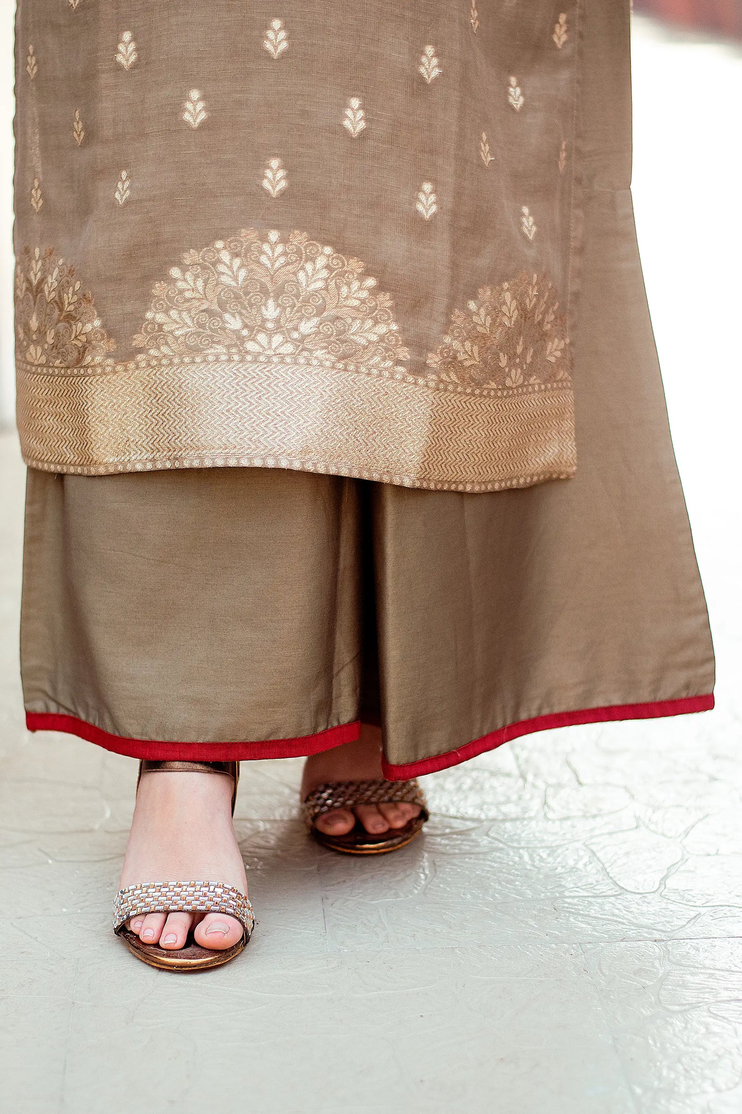 Close-up of palazzo trousers with a delicate taupe zari weave pattern, paired with sandals