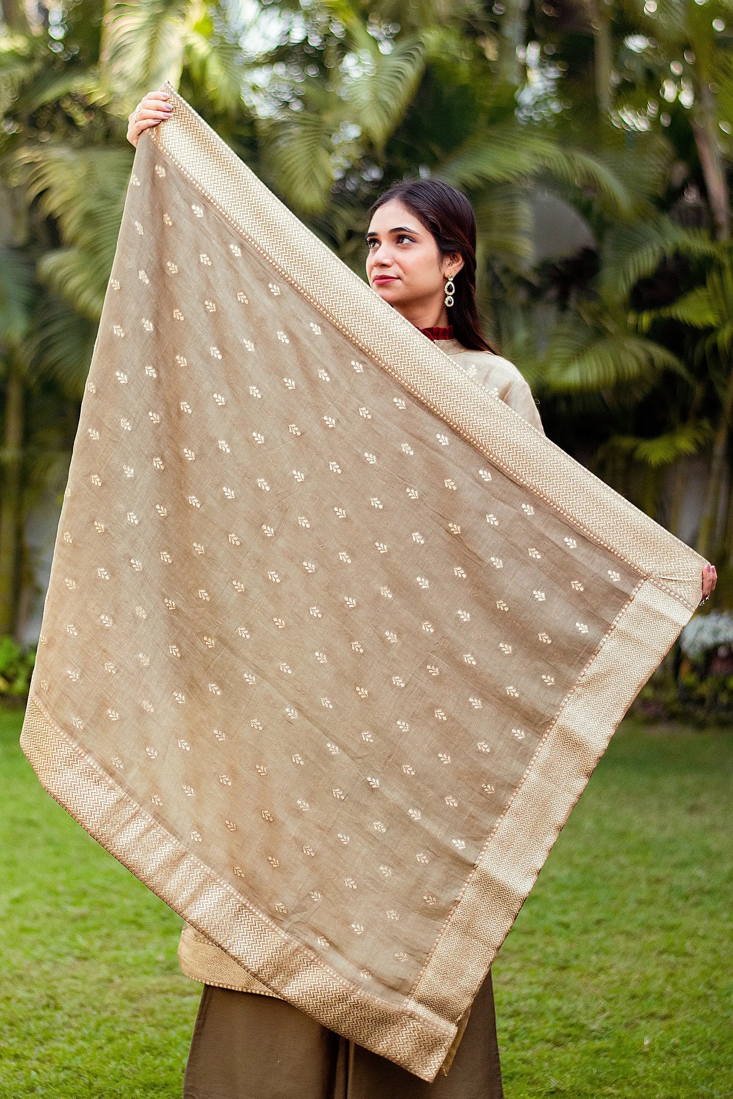 A model showing a linen dupatta with a beautiful taupe zari weave pattern