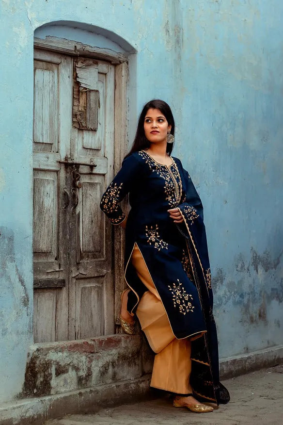 Full-length right side pose of an Indian woman wearing a dark blue chanderi kurta & dupatta with applique work and golden palazzo