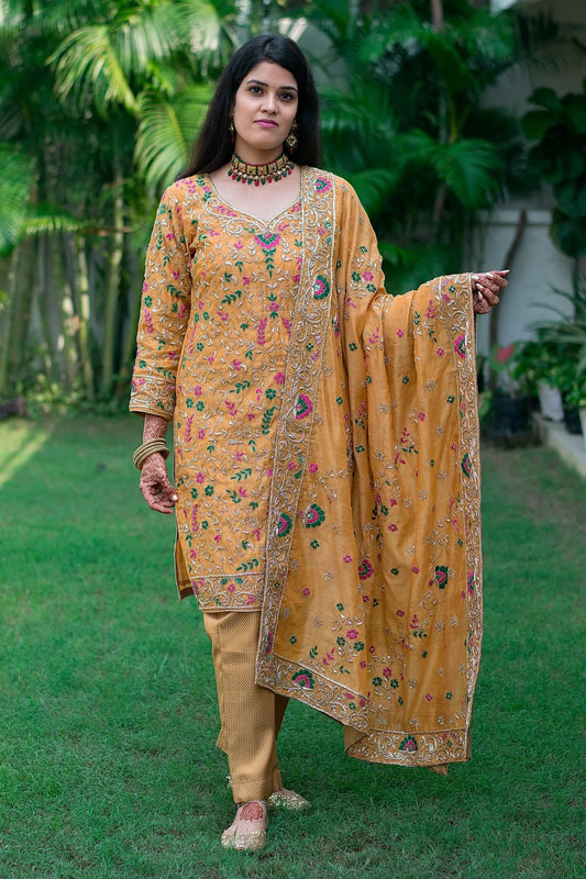 A woman wearing a stunning Mustard Zardozi & Resham Embroidered Chanderi Kurta And Dupatta With Brocade Trousers.