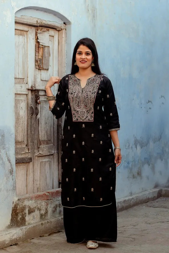 An elegant woman dressed in a stylish black silk kurta with Zardozi work, a black Chanderi dupatta, and palazzo pants.