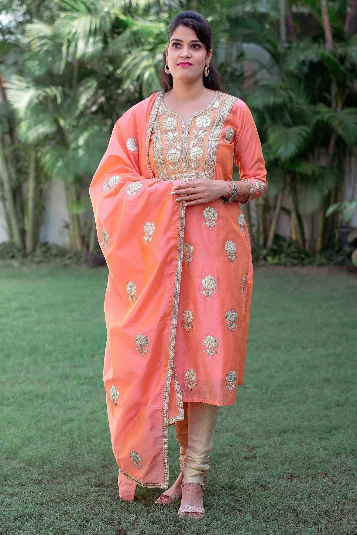 A woman in a Peach Chanderi Kurta with Gota Work and a Dupatta, paired with a Golden Churidar.