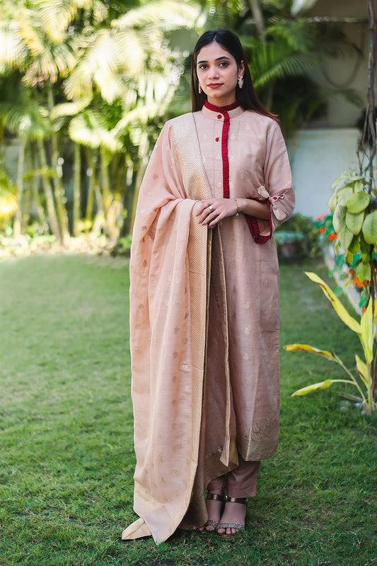 A woman wearing a beige kurta set with intricate zari embroidery on linen weave fabric