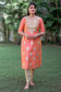 An Indian woman dressed in a Peach Chanderi Kurta and Dupatta with intricate Gota Work, paired with a Golden Churidar.