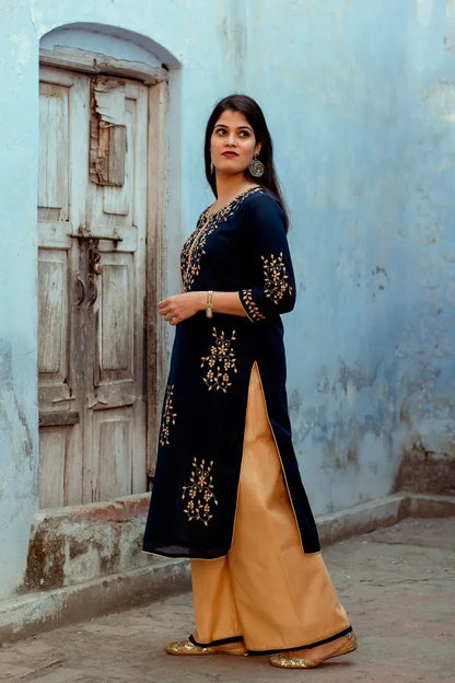 An Indian woman in a side pose wearing a Dark Blue Chanderi Kurti with applique work and Golden Chanderi Palazzo, full length is visible.