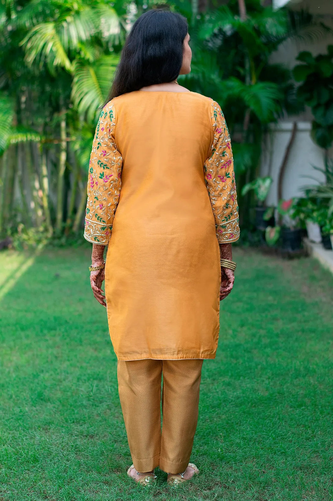 Woman dressed in a beautifully embroidered Mustard Kurta and Dupatta with matching Brocade Trousers.