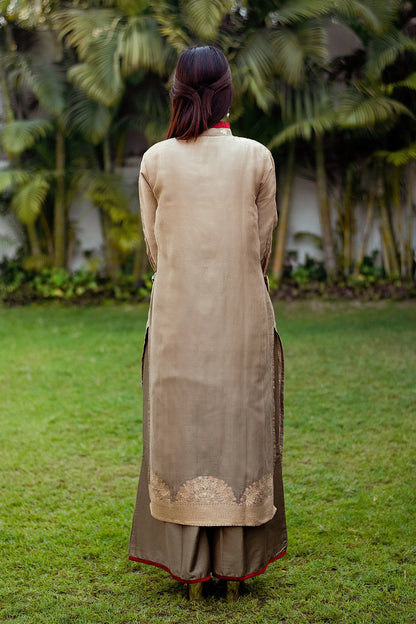 A model in a back pose, showcasing a linen kurta with a beautiful taupe zari weave pattern