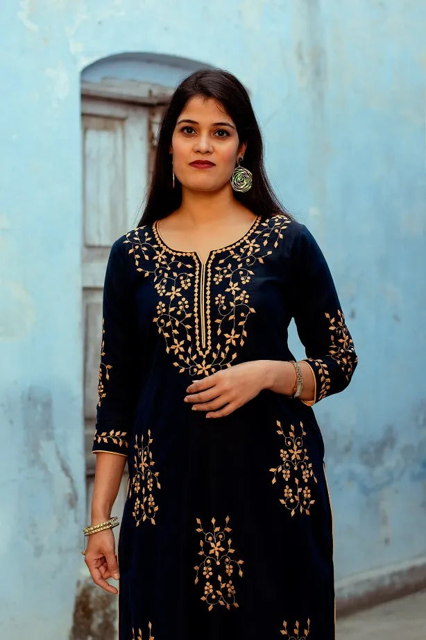 Indian woman poses where half of  front of the dark blue chanderi kurta with applique work is visible.