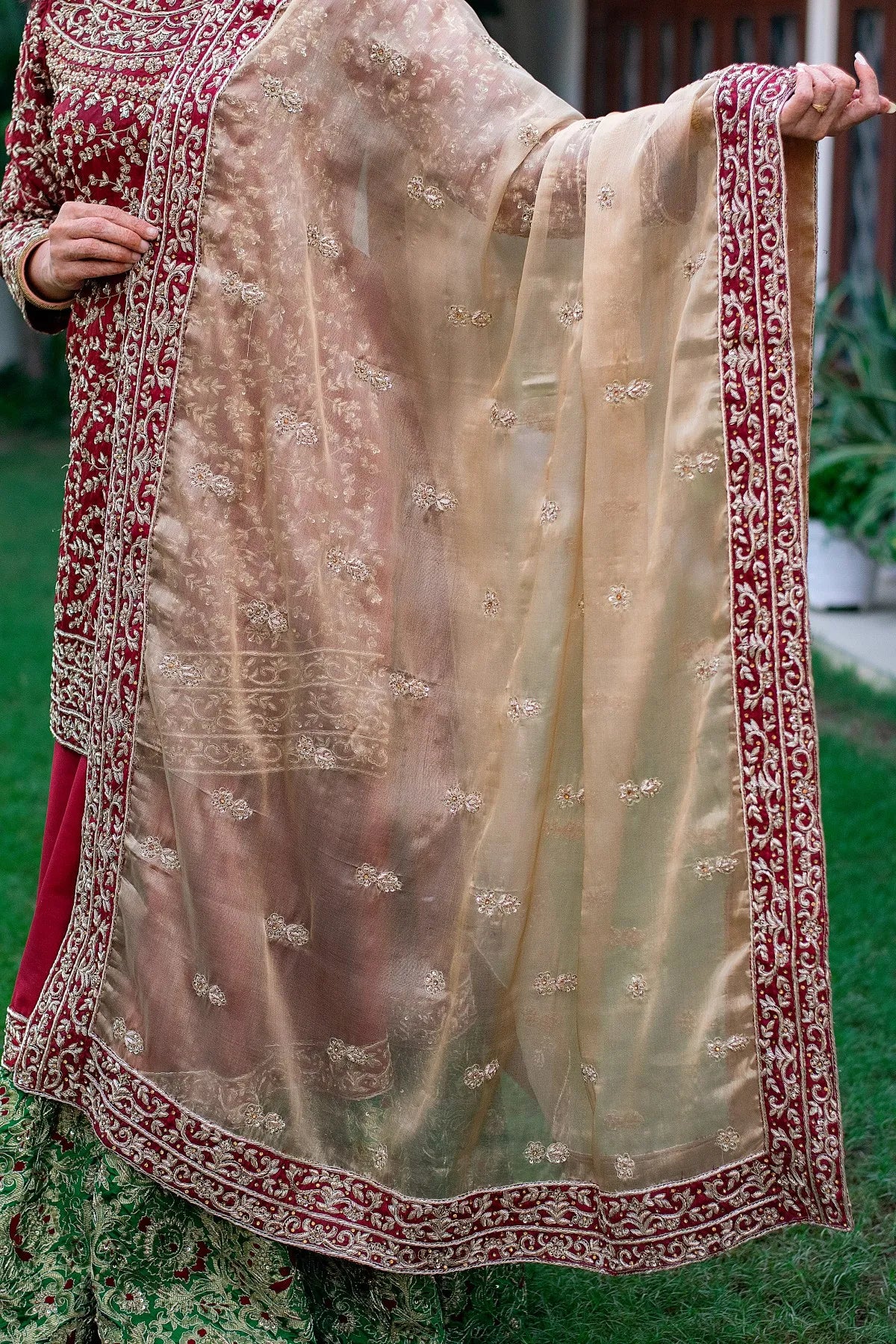 A traditional Indian outfit consisting of a maroon silk Gharara and tissue dupatta, carefully crafted with exquisite details.