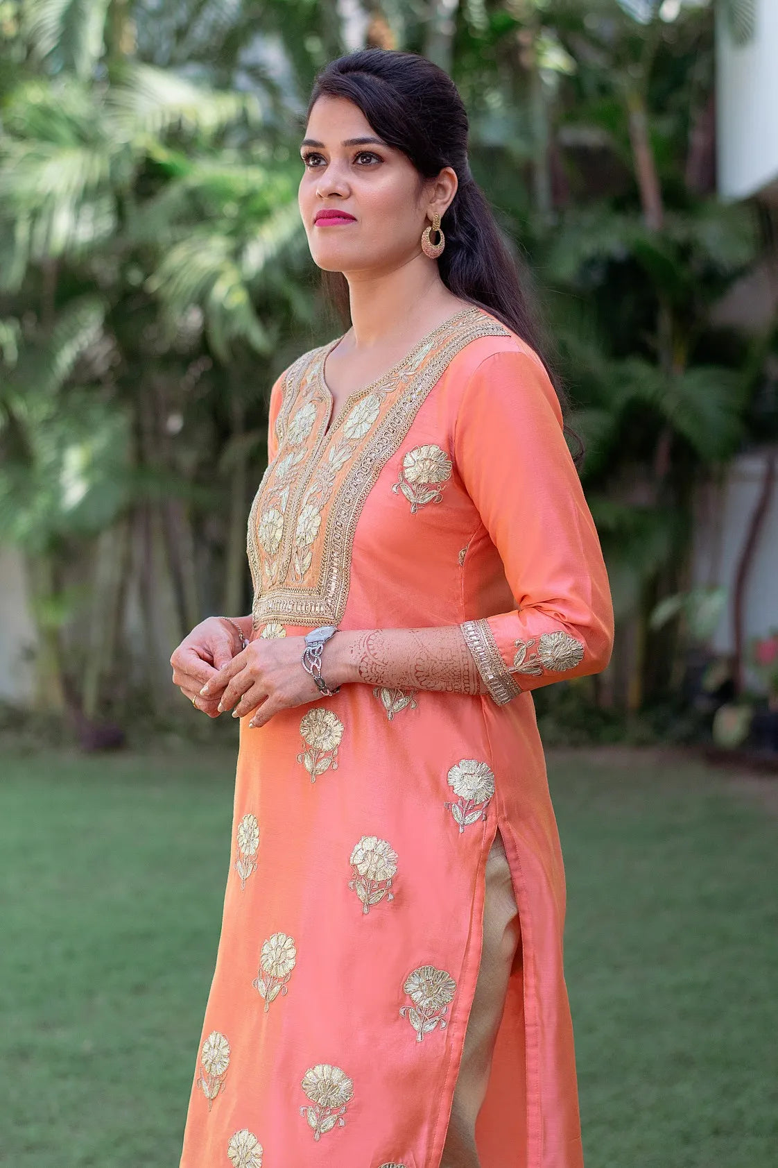 A woman sporting a Peach Chanderi Kurta and Dupatta with delicate Gota Work, along with a Golden Churidar.