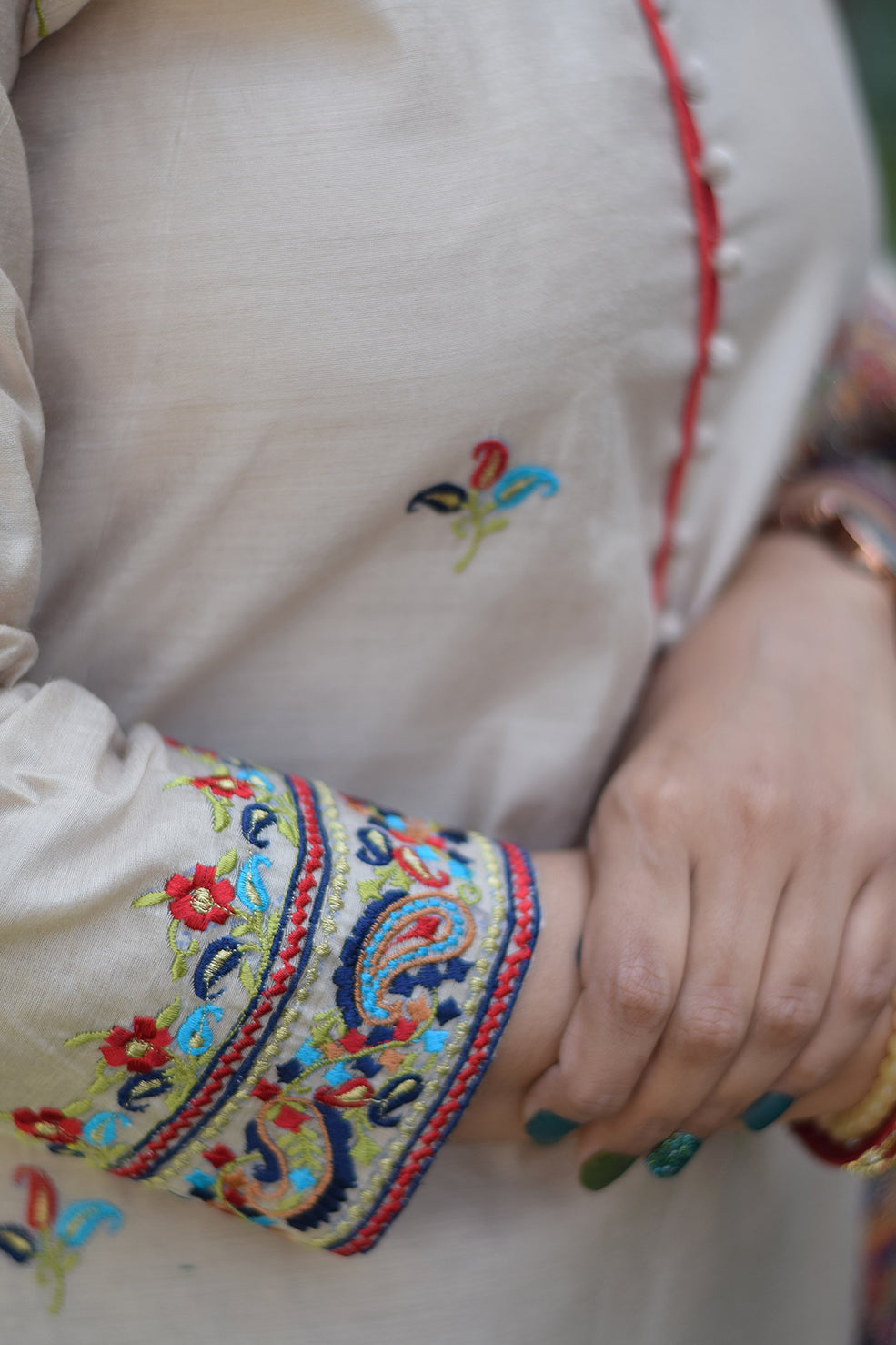 Beige kurta paired with blue silk jamawar dupatta is worn by a woman standing in a field.