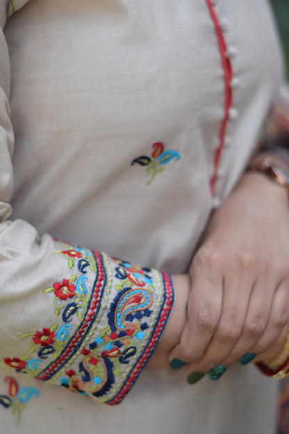 Beige kurta paired with blue silk jamawar dupatta is worn by a woman standing in a field.
