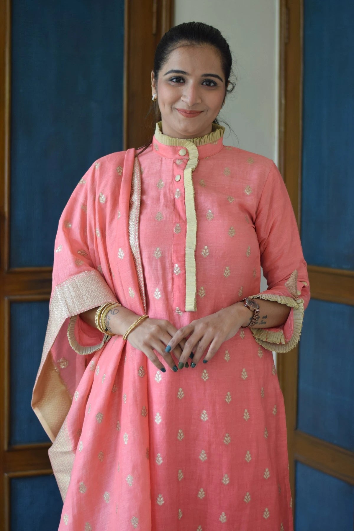 A woman wearing a peach-colored linen kurta with intricate embroidery.
